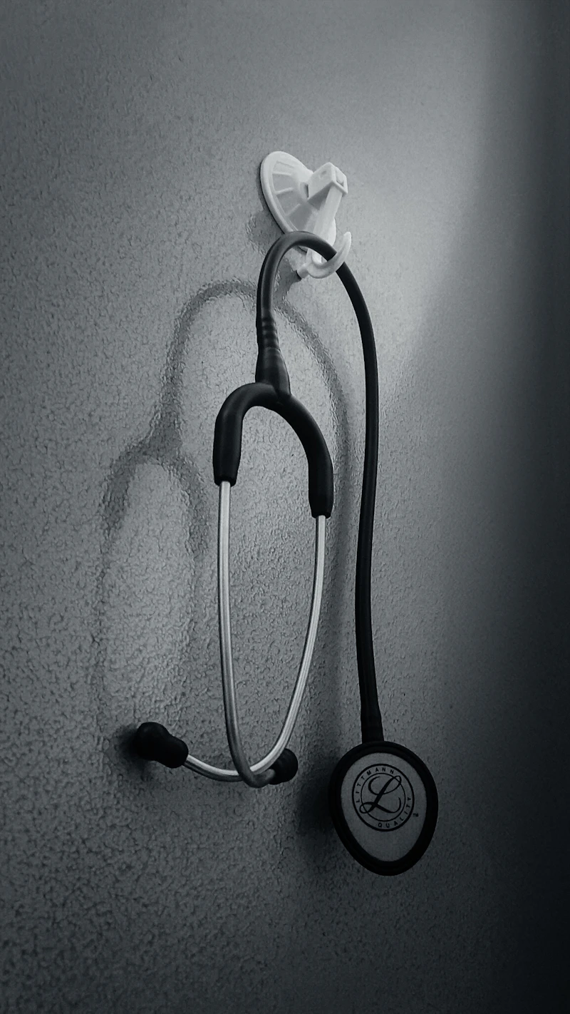 A stethoscope hanging from a hook on a wall, in black and white